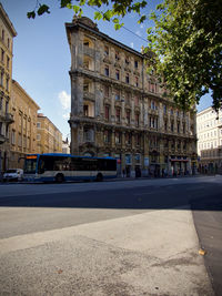 Cars on road by buildings against sky in city