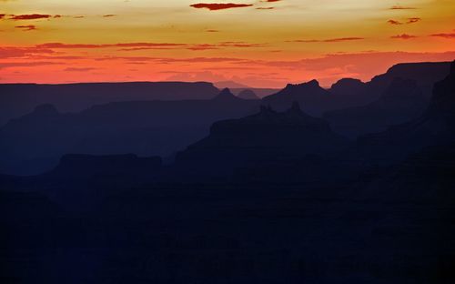 Scenic view of silhouette mountains against orange sky