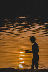 Silhouette man standing on beach against sky at night