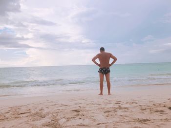 Rear view of shirtless man standing on beach