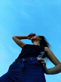 Low angle view of woman standing against blue sky