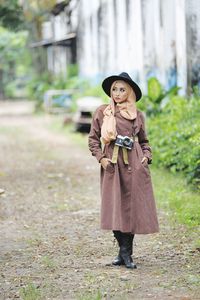 Portrait of young woman wearing hat standing on field