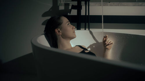 Portrait of young woman sitting on window