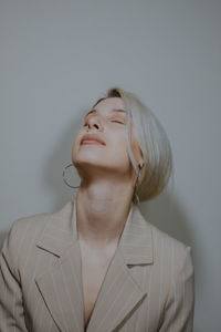 Close-up of young woman wearing blazer against wall