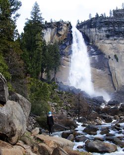 Rear view of man standing against waterfall