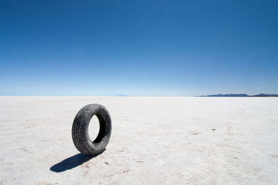 Cross on beach against clear blue sky