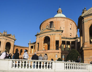 Group of people in historic building against clear blue sky