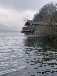 House on lake by building against sky