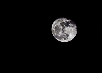 Low angle view of full moon against dark sky