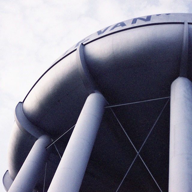 low angle view, sky, built structure, architecture, part of, no people, day, modern, outdoors, cropped, building exterior, metal, tall - high, travel, close-up, transportation, lighting equipment, cloud - sky, tower, technology