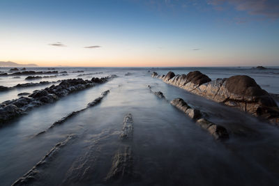 Blurred motion of sea over rocks during sunset