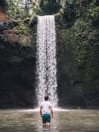 Rear view of man looking at waterfall