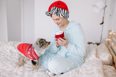 Midsection of woman with dog sitting at home