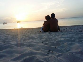 Rear view of couple sitting on beach