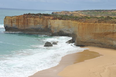 Rock formation on beach against sky