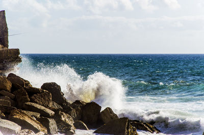 Wave blasting at rock at a scenic view of sea against sky