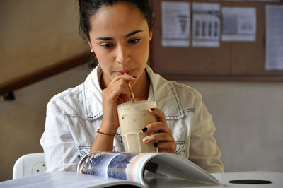 Portrait of young woman drinking and reading