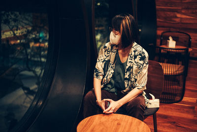 Young woman sitting on chair at night