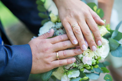 Cropped hands of couple on bouquet