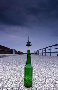 Close-up of beer bottle on snow against sky