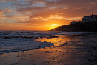 Scenic view of beach against cloudy sky at dusk