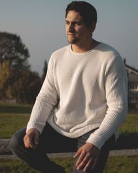 Young man wearing hat while sitting on land