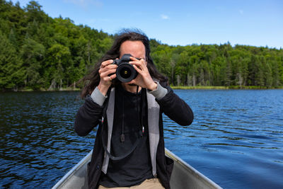 Portrait of man photographing against lake