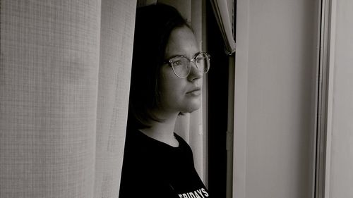 Young woman looking through window