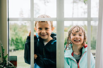 Brother and sister stood looking through a window whilst playing