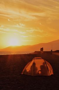 Friends in dome tent at beach during sunset