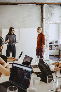 Young female entrepreneur giving presentation to colleagues in office