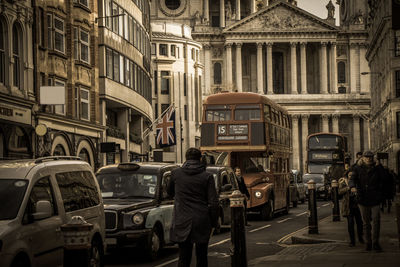 People walking on street amidst buildings in city