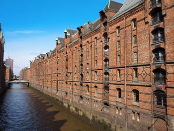 Canal amidst buildings against sky in city