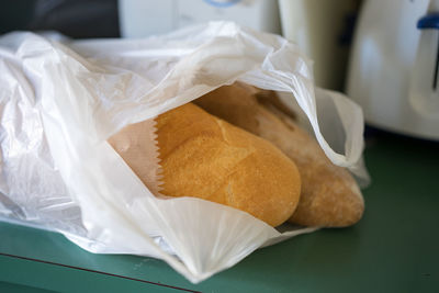 Close-up of fresh breads in shopping bag on table