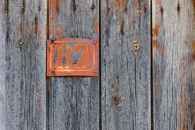 Full frame shot of old door with rusty metallic number