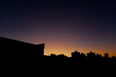 Silhouette cityscape against sky at sunset