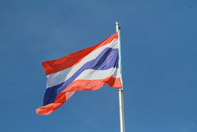 Low angle view of thai flag against blue sky