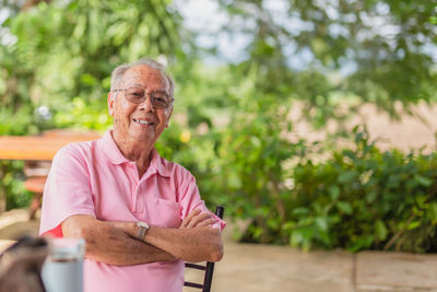 Portrait asian elderly man 83 years old with toothy smile sitting outdoor in the garden