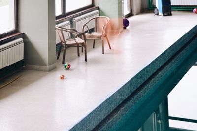 Empty chairs and table against window in building