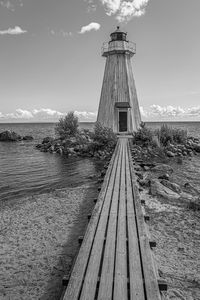 Walkway leading towards sea against sky