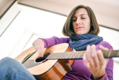 Woman playing guitar at home