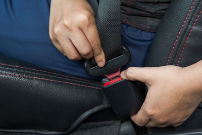 Midsection of woman wearing seat belt in car