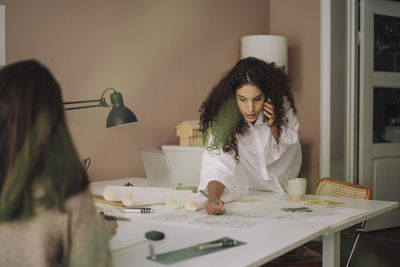 Portrait of smiling young woman using mobile phone at home