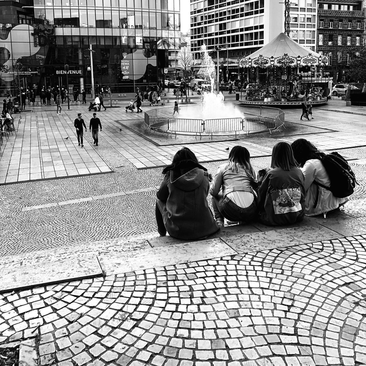 group of people, architecture, women, city, real people, adult, built structure, building exterior, men, lifestyles, street, people, crowd, city life, day, sitting, rear view, footpath, cobblestone, outdoors, paving stone, waiting