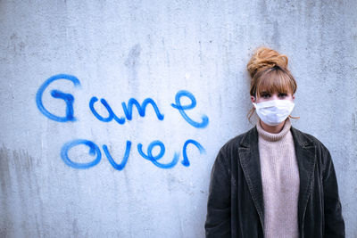 Portrait of a young woman standing against wall