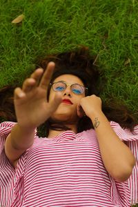 Portrait of young woman reaching while lying on grass