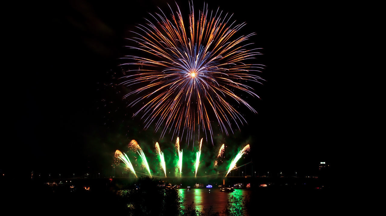 night, firework, illuminated, firework display, event, arts culture and entertainment, celebration, motion, exploding, firework - man made object, glowing, long exposure, no people, water, architecture, sky, nature, reflection, multi colored, light, outdoors, sparks, new year's eve, explosive