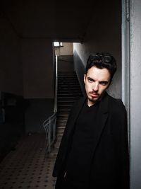 Portrait of young man standing against wall