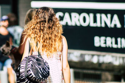 Rear view of woman standing against graffiti in city