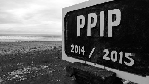 Information sign on beach against sky